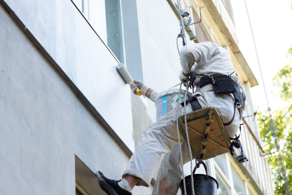 climber builder paints the facade of the building, close-up